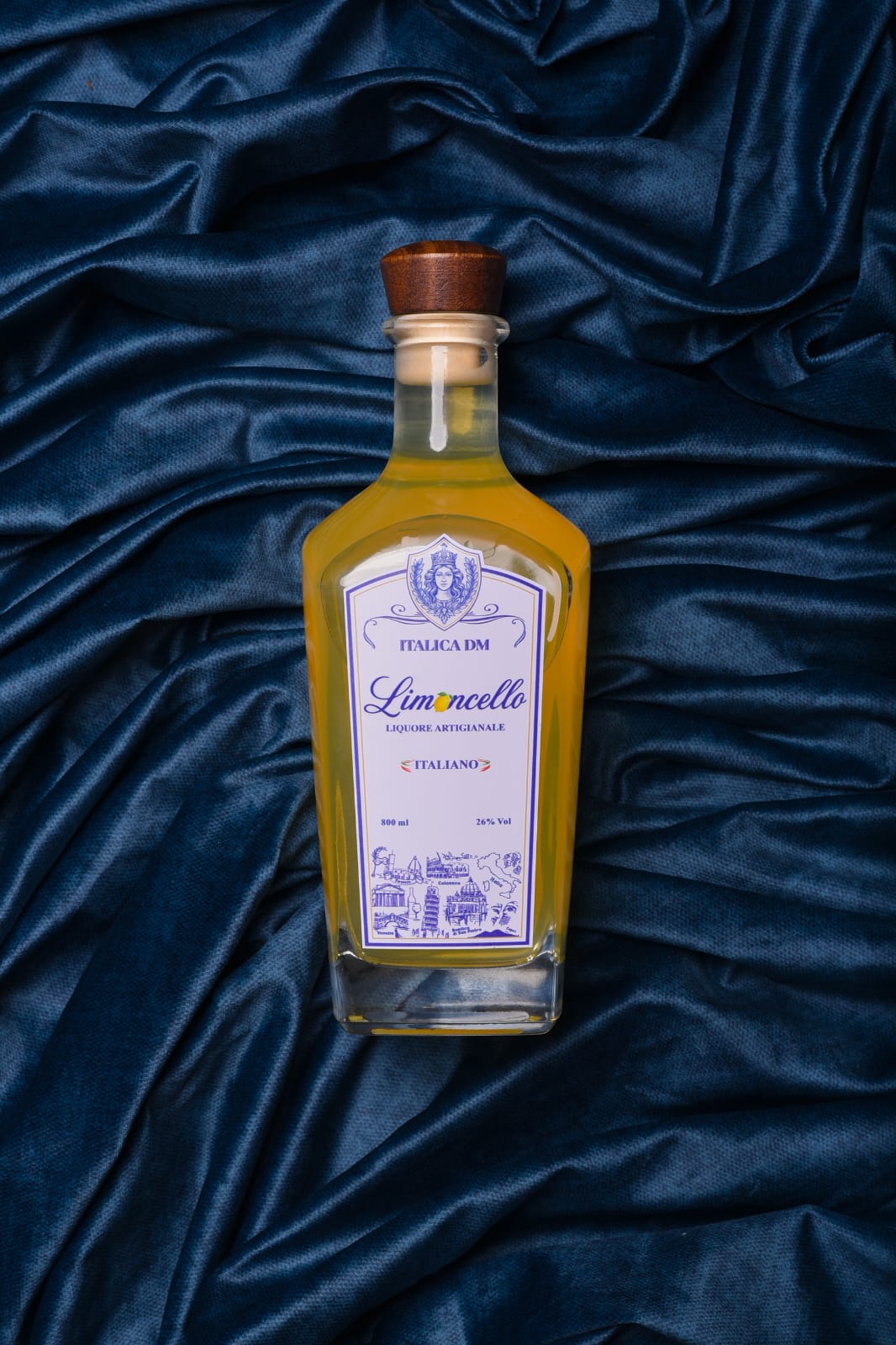 Garrafa de Limoncello Italica DM em cena elegante sobre veludo azul, clima de brinde e hospitalidade