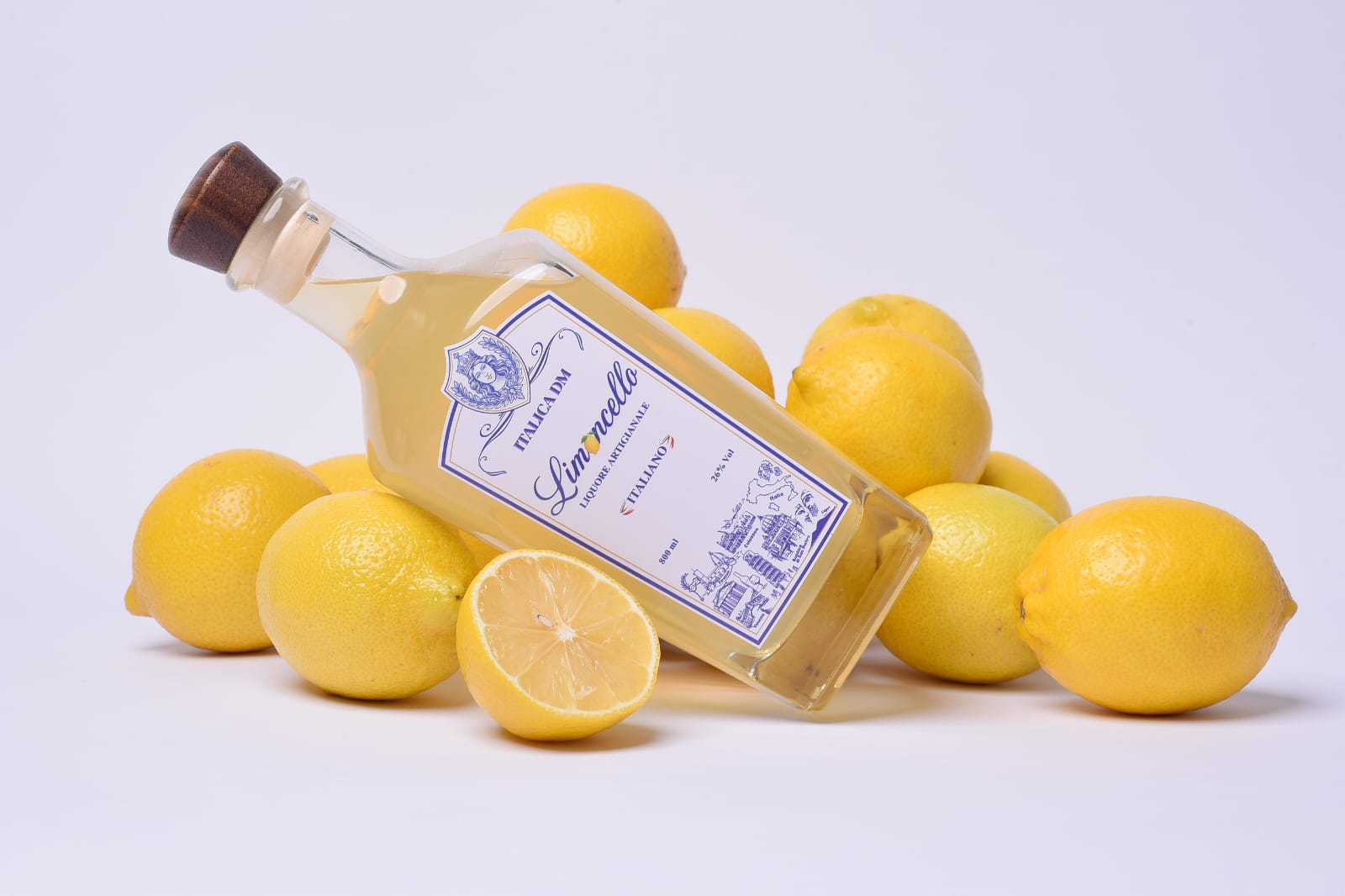 Garrafa de Limoncello Italica DM deitada entre limões, fundo claro
